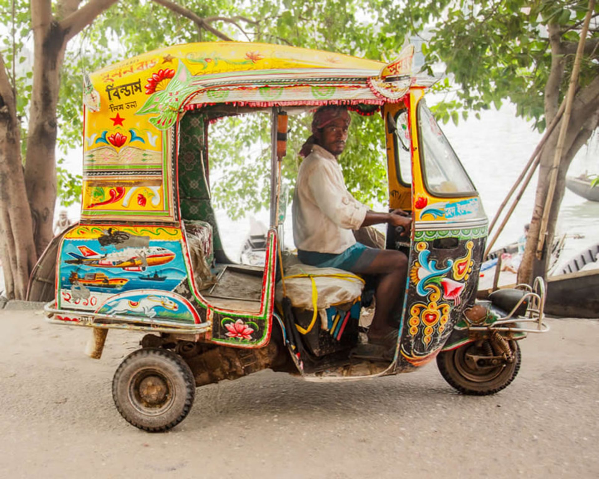 مردی در اتو ریکشای زرد رنگ نقاشی شده