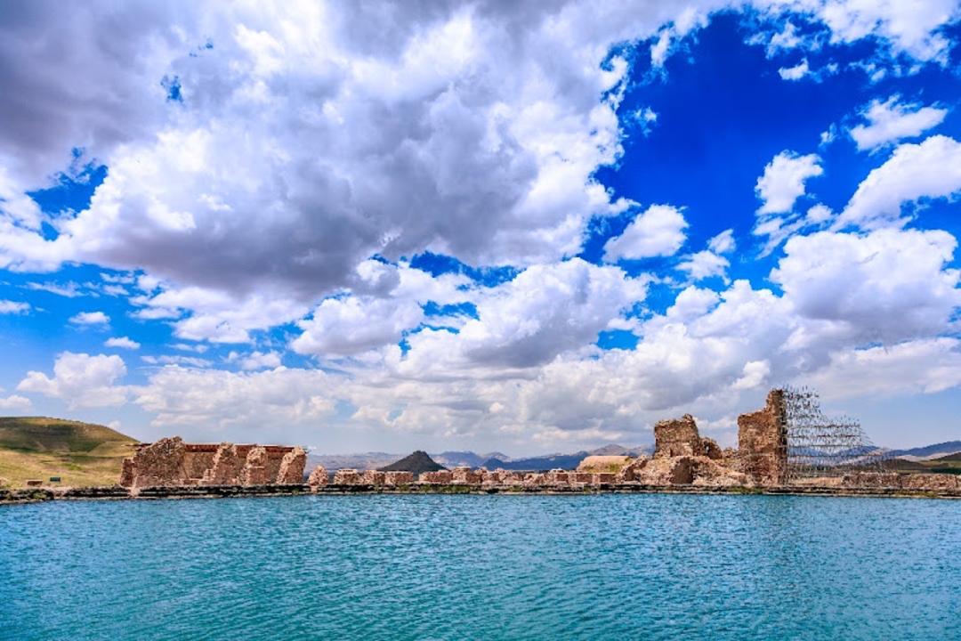 آب شفاف دریاچه تخت سلیمان با ابرهای سفید در آسمان