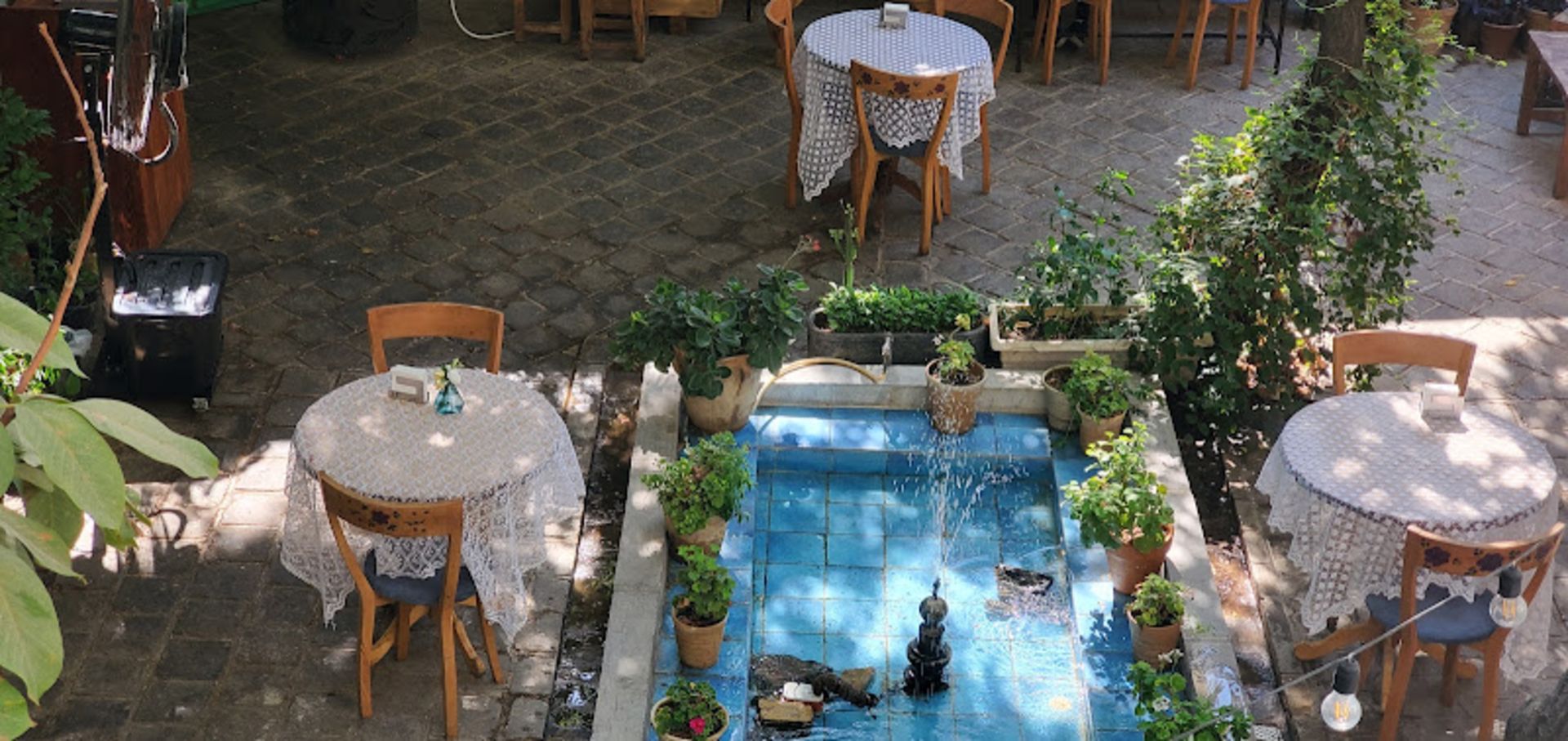 فضای بیرونی کافه حوالی با میزهای چوبی