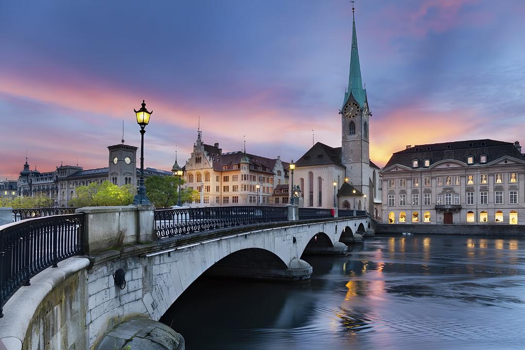 پل سنگی و ساختمان‌های تاریخی در کنار رودخانه در شهر زوریخ (Zurich)
